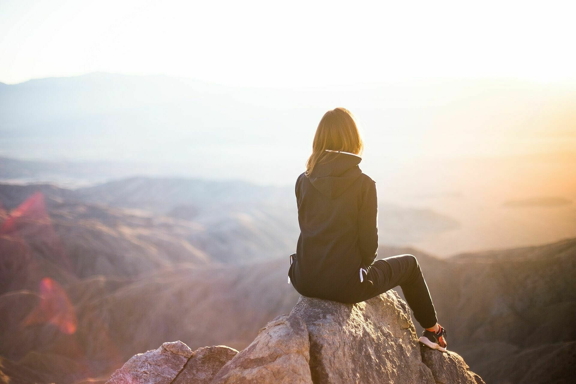 Frau blickt auf ein Bergpanorama bei Sonnenauf- oder Untergang
