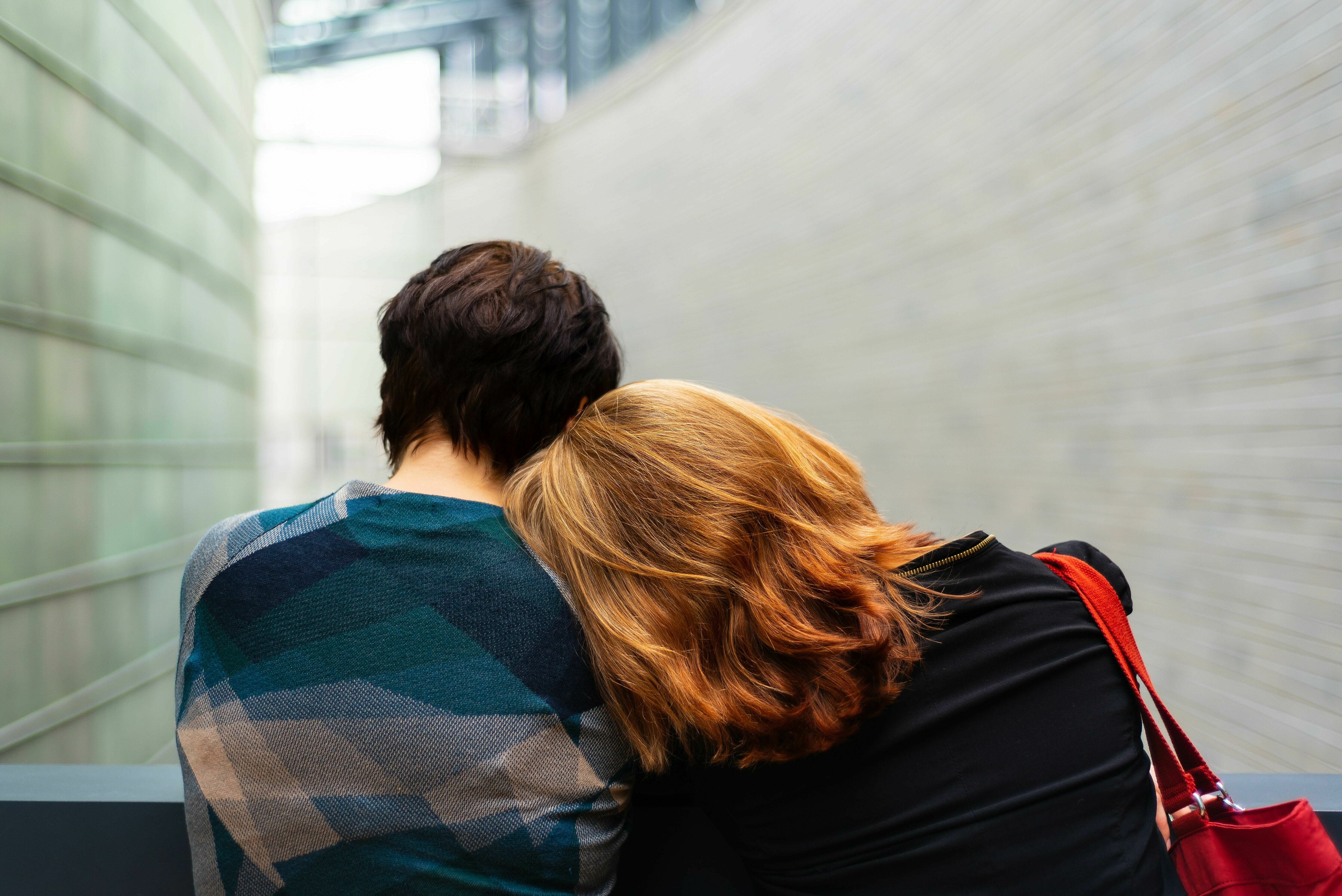 Mann und Frau legen die Köpfe gegenseitig auf die Schulter ab, sichtbar von hinten