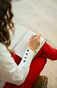 Vogelperspektive: Frau schreibt etwas in einen Planer bzw. ein Notizbuch