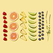 Verschiedene Früchte in Reihen nebeneinander auf gelblichem Hintergund gelegt: Himbeeren, Zitrusfrucht, Ananas, Limette, Blaubeeren, Lavendel