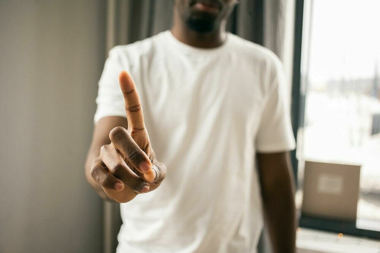 Hand eines Mannes im Fokus, der nur den Zeigefinger nach oben zeigt
