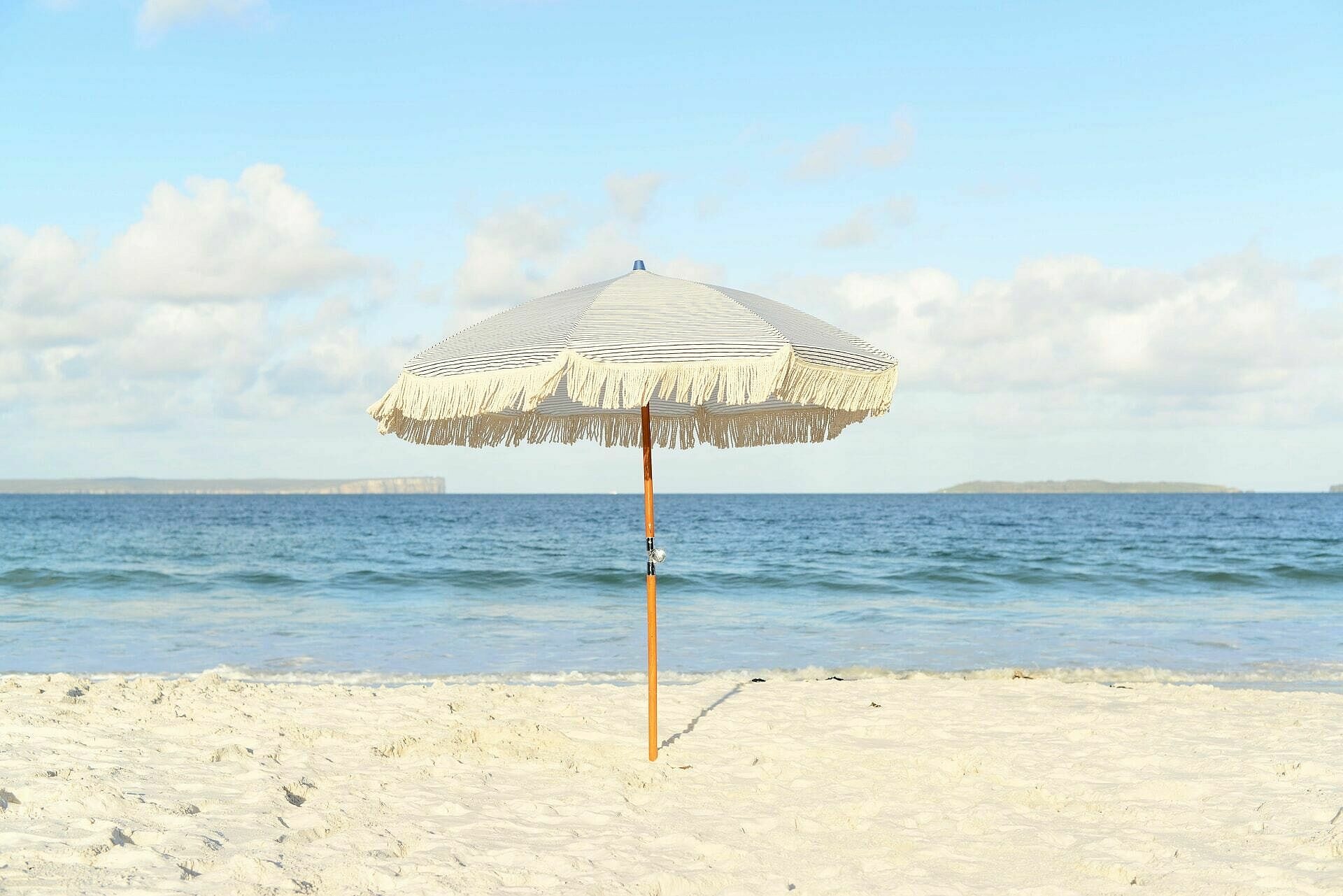 Sonnenschirm am Strand, im Hintergrund das Meer