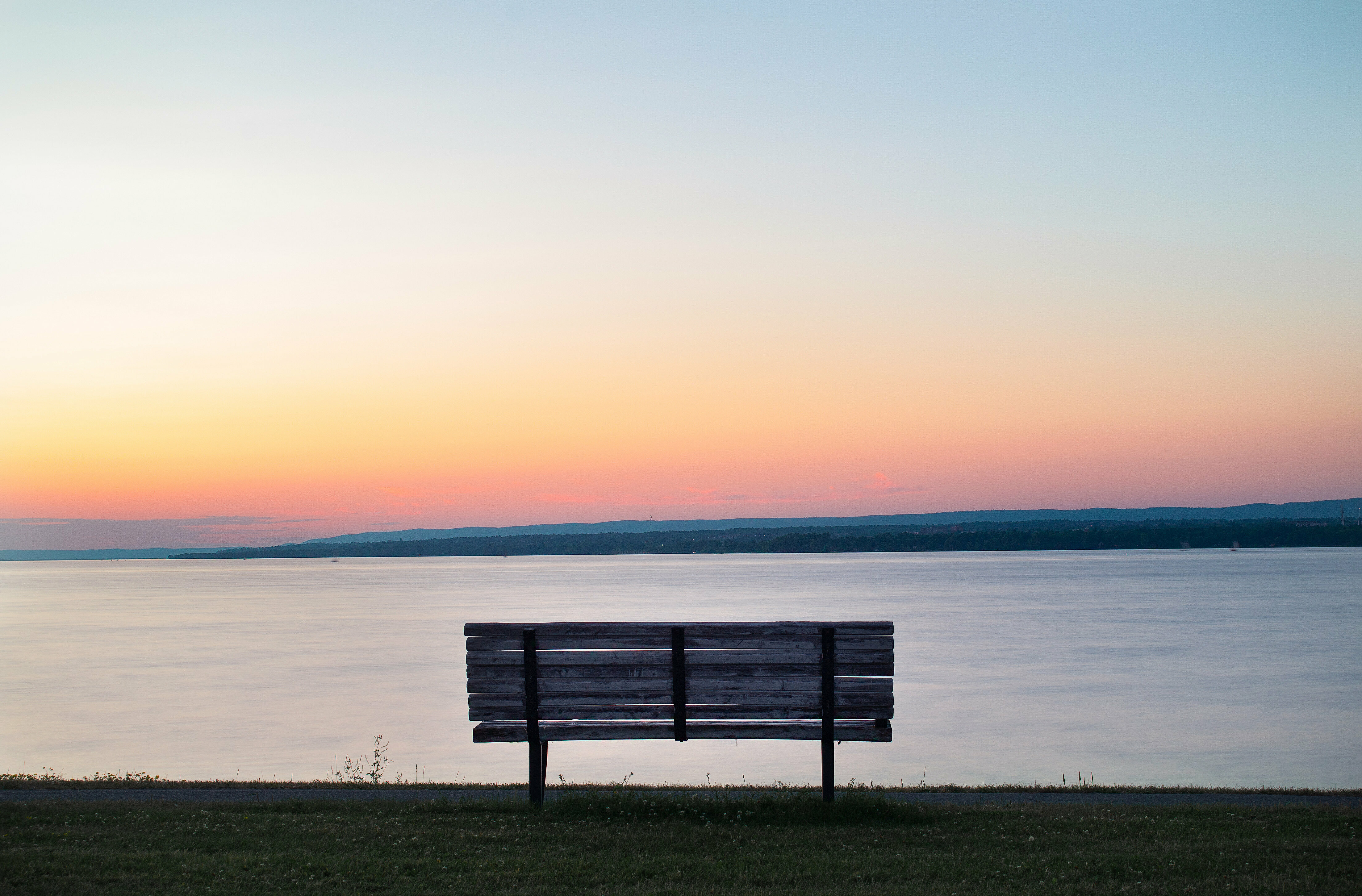 Sitzbank vor einem Sonnenuntergang über dem Wasser